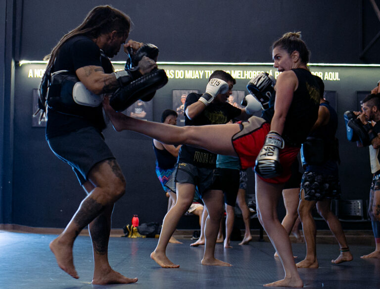 Mulher treinando artes marciais em academia durante aula de luta
