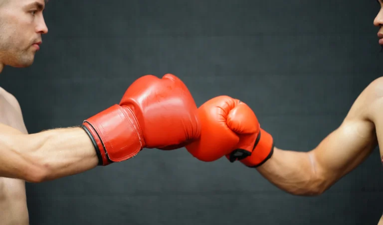 Duas pessoas de boxe trocando socos com luvas vermelhas, de frente uma para a outra, demonstra força e preparação para treinamento de boxe.