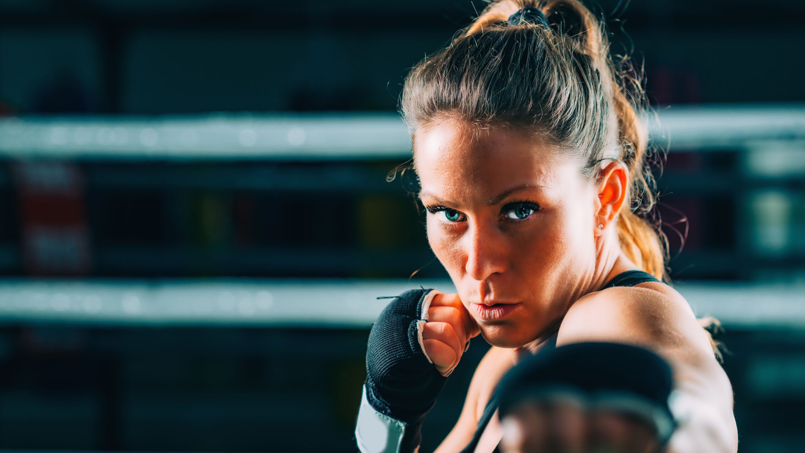 Mulher lutadora treinando boxe na academia, demonstrando força, foco e determinação em um ambiente de treino, ideal para quem busca fitness e autodefesa.