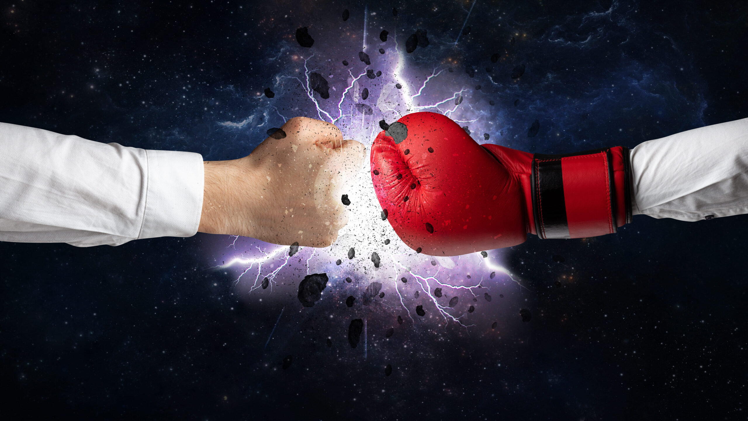 Imagem de duas mãos em processo de luta, uma com uma luva de boxe vermelha e outra sem luva, com impacto e raios ao fundo, simbolizando confronto e resistência.