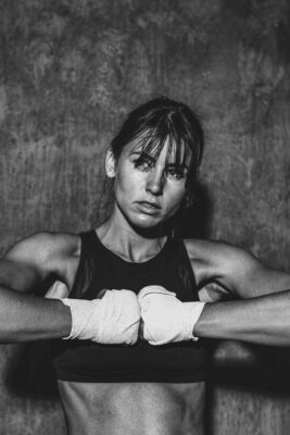 Mulher atleta fitness treinando força com boxe, focada e determinada, em ambiente interno.