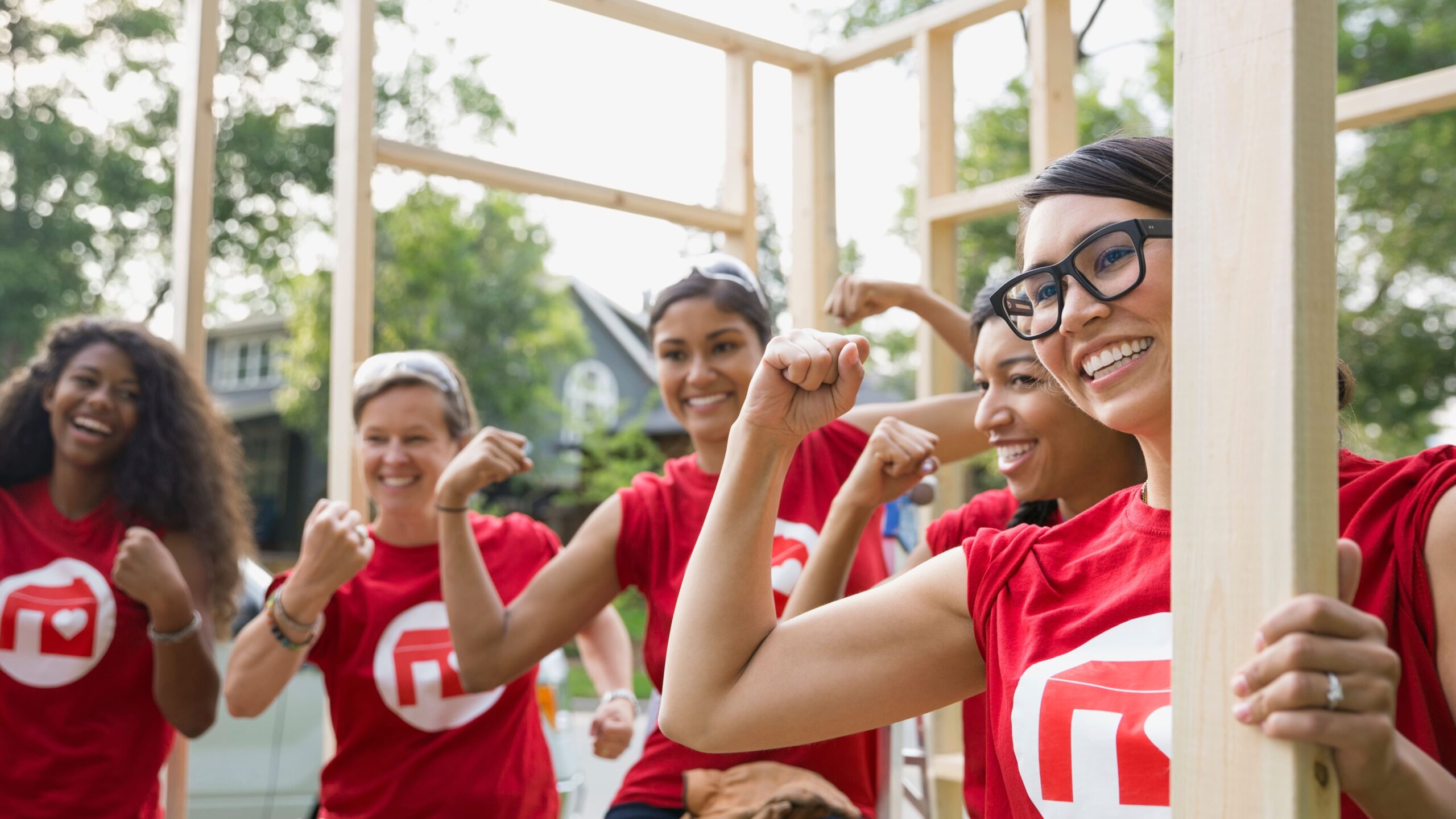 Grupo de mulheres fitness celebrando ao ar livre durante treinamento, destacando força, saúde e empoderamento feminino, vestindo camisetas vermelhas.