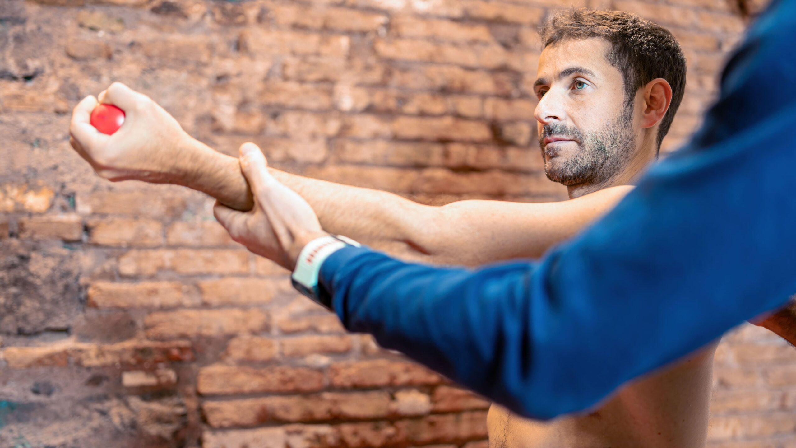 Homem fazendo treinamento com foco na preparação física e força muscular em ambiente interno com parede de tijolos.