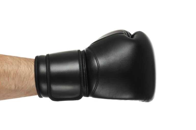 Vista lateral de braço usando uma luva de boxe preta limpa e conservada contra fundo branco.