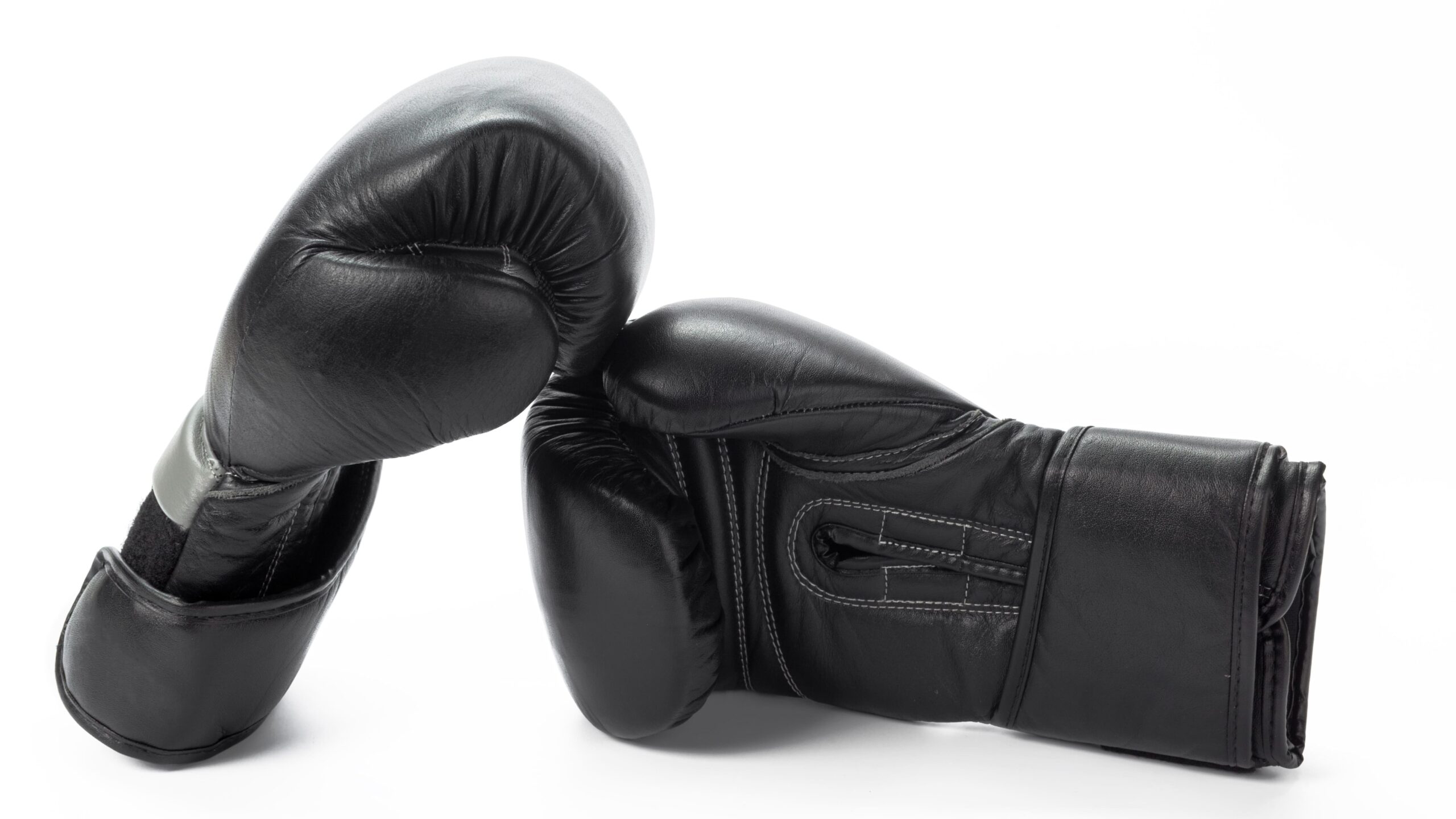 Par de luvas de boxe pretas apoiadas entre si sobre fundo branco, mostrando a área da palma e das costuras.