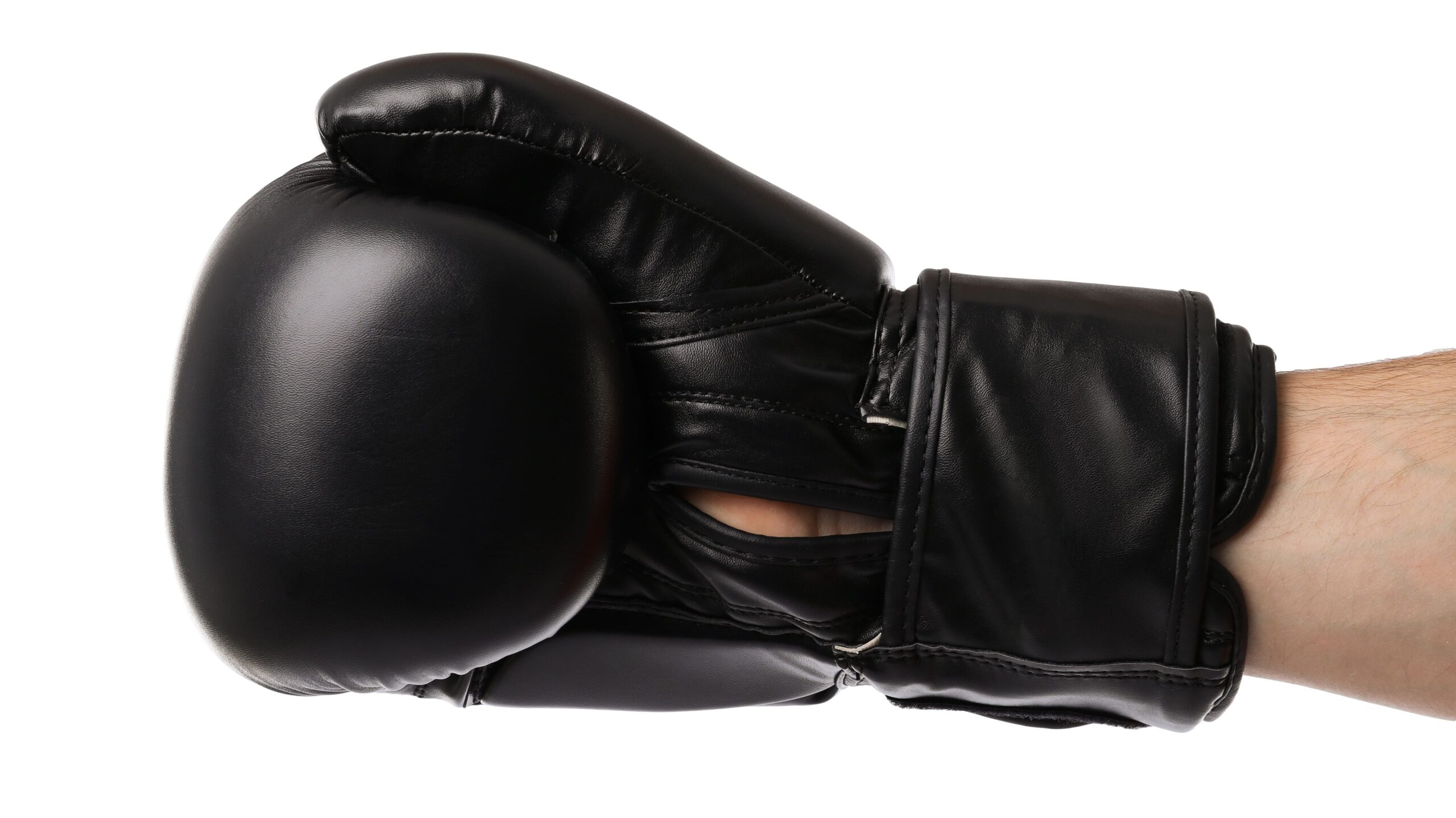 Mão usando luvas de boxe pretas, com punho ajustável e formato de protetor acolchoado, em fundo branco. Foto de equipamento esportivo para treino ou luta.